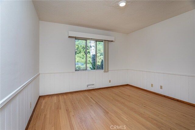 empty room with a textured ceiling and hardwood / wood-style flooring