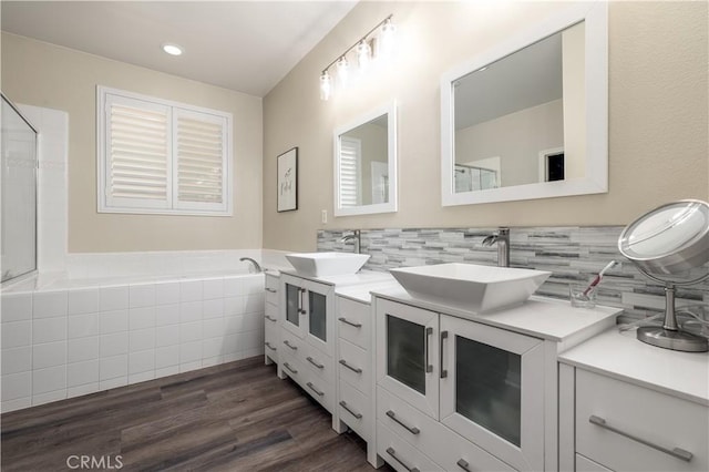 bathroom with double vanity, wood finished floors, a sink, and decorative backsplash