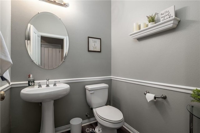 half bath with wood finished floors, toilet, and baseboards