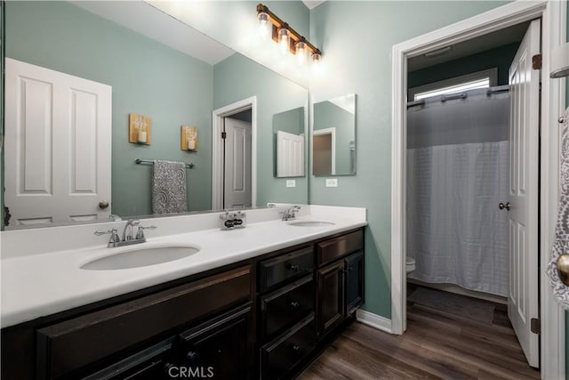 full bath featuring double vanity, wood finished floors, a sink, and toilet