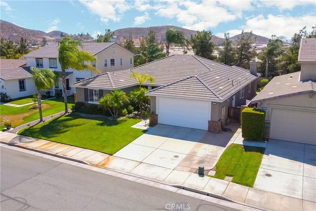 view of front of property with driveway, a front yard, a mountain view, and stucco siding