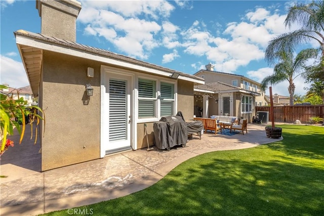 rear view of property featuring a patio, fence, a yard, outdoor lounge area, and stucco siding