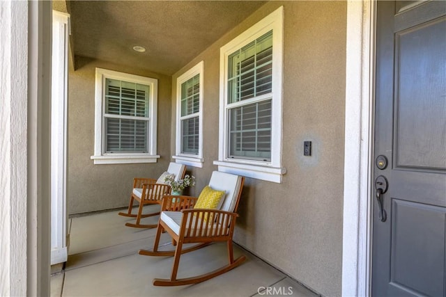 view of exterior entry featuring covered porch and stucco siding