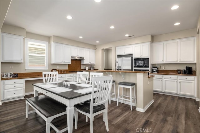 dining space with dark wood finished floors, built in desk, and recessed lighting