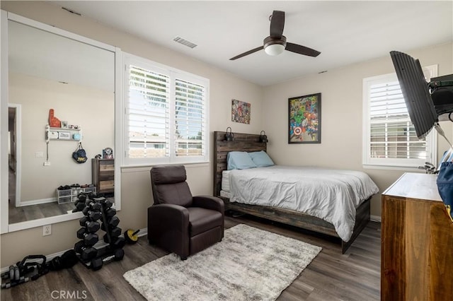 bedroom featuring baseboards, multiple windows, visible vents, and wood finished floors