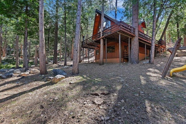 rear view of property featuring a wooden deck and a playground