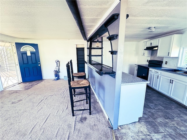 kitchen with black range with electric cooktop, sink, white cabinets, and dark colored carpet