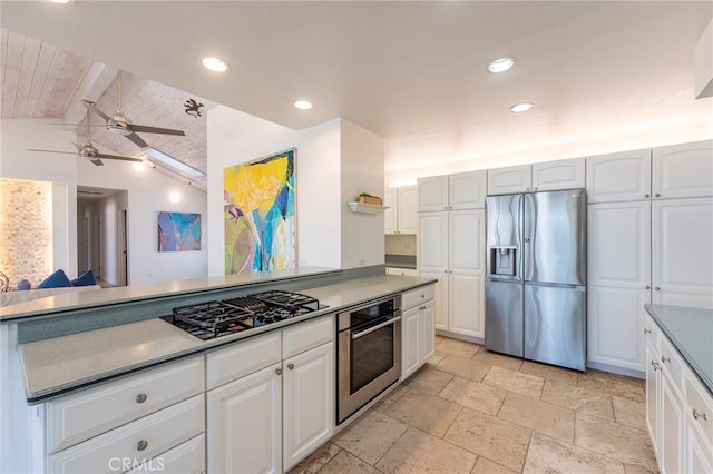 kitchen featuring vaulted ceiling, stainless steel appliances, white cabinetry, and ceiling fan