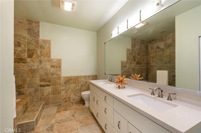 bathroom with vanity, toilet, and tile walls