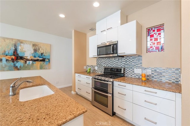 kitchen featuring white cabinetry, sink, stainless steel appliances, and light stone counters