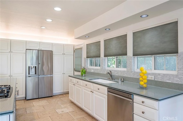 kitchen with backsplash, sink, white cabinetry, and stainless steel appliances