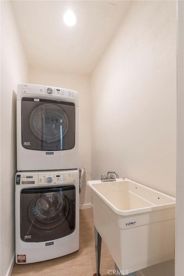 washroom with sink, stacked washer and clothes dryer, and light hardwood / wood-style flooring