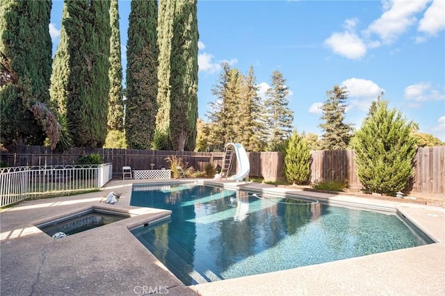 view of pool featuring a fenced in pool, a water slide, a fenced backyard, and an in ground hot tub