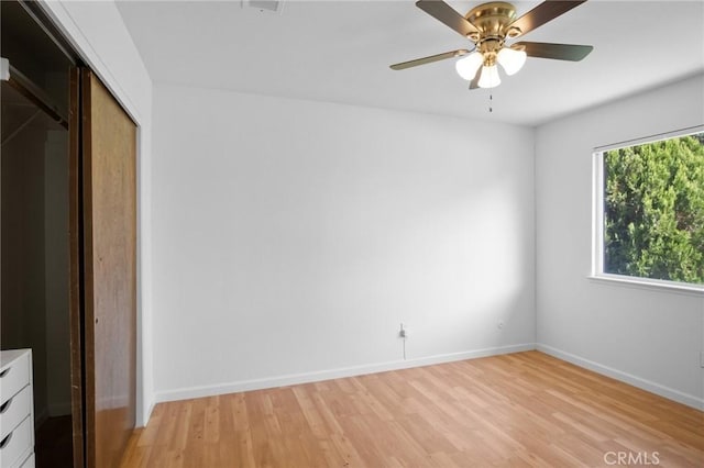 unfurnished bedroom with light wood-type flooring, ceiling fan, baseboards, and a closet