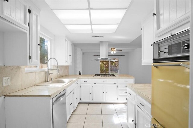 kitchen featuring light tile patterned floors, decorative backsplash, island range hood, ceiling fan, and sink