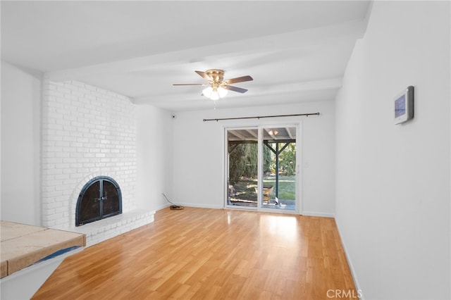 unfurnished living room with ceiling fan, light hardwood / wood-style flooring, a fireplace, and brick wall