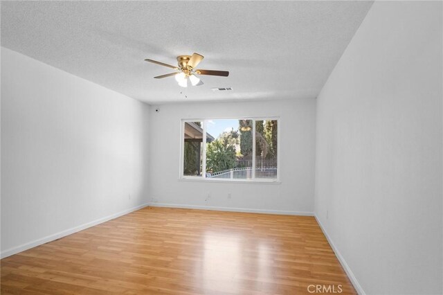 empty room with ceiling fan, a textured ceiling, and light hardwood / wood-style floors