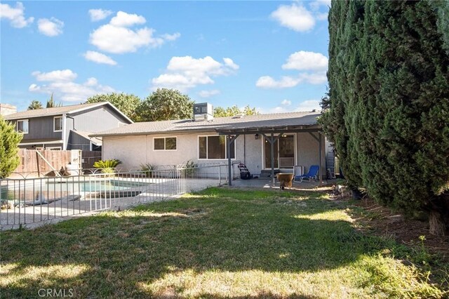 back of house featuring a fenced in pool, a patio area, and a yard