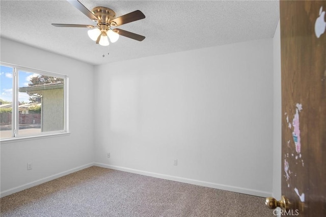 carpeted spare room featuring a textured ceiling, ceiling fan, and baseboards