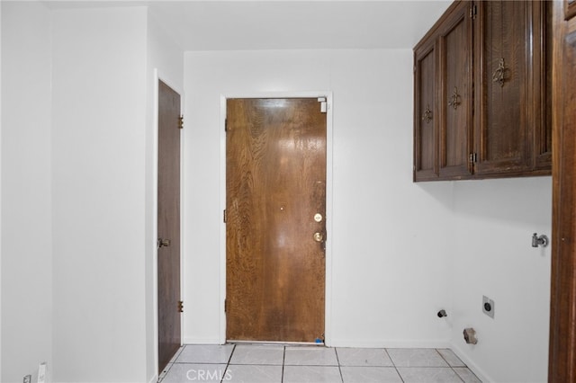 clothes washing area with electric dryer hookup, light tile patterned floors, and cabinets