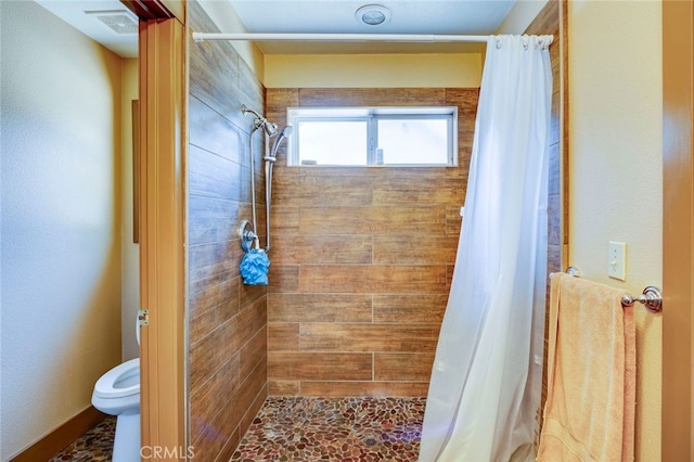 bathroom with a shower with shower curtain and toilet