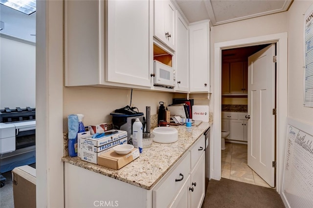 kitchen featuring white cabinets, light tile patterned floors, and light stone countertops