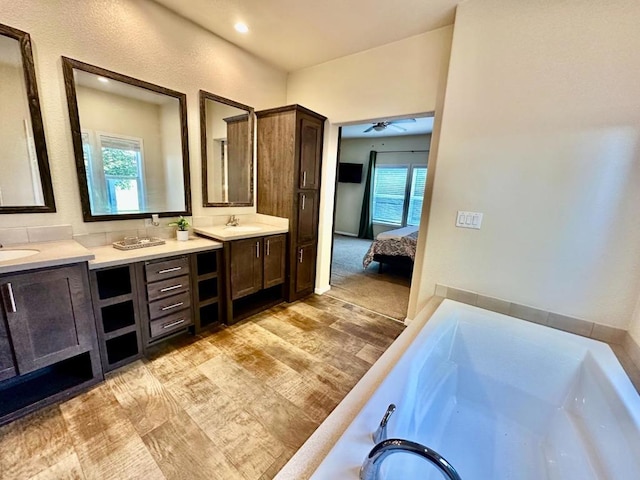 bathroom featuring a washtub, hardwood / wood-style flooring, ceiling fan, and vanity