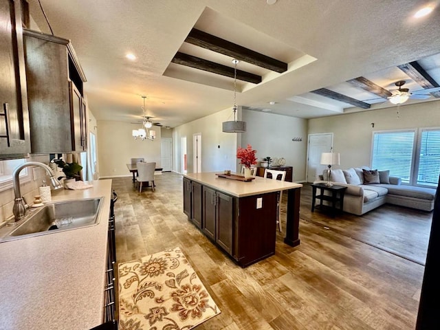 kitchen with a kitchen island, light hardwood / wood-style floors, sink, hanging light fixtures, and dark brown cabinets