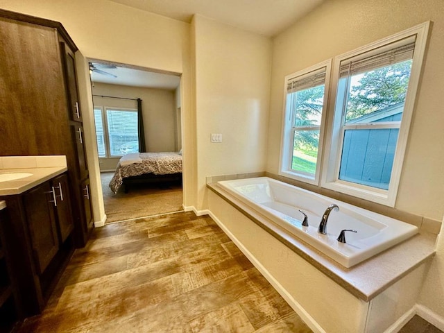 bathroom featuring ceiling fan, a bathtub, hardwood / wood-style flooring, and vanity