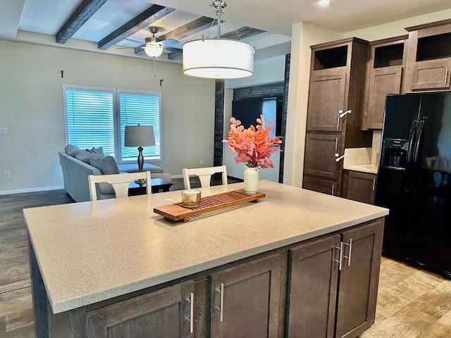 kitchen with a center island, black refrigerator with ice dispenser, light hardwood / wood-style floors, ceiling fan, and beam ceiling