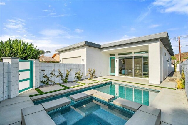 rear view of property with a swimming pool with hot tub and a patio area