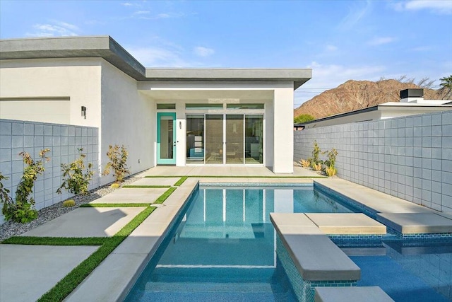 view of swimming pool with a mountain view, a patio area, and a hot tub