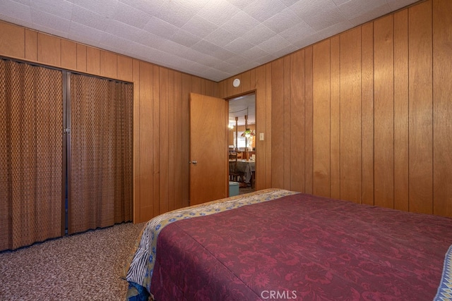 bedroom featuring a closet, wooden walls, and carpet flooring