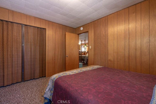 bedroom featuring carpet floors, wooden walls, and a closet