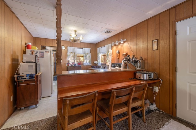 bar featuring light carpet, wooden walls, a notable chandelier, and white fridge