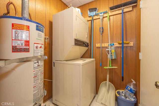 washroom with wood walls, water heater, stacked washing maching and dryer, and light tile patterned floors