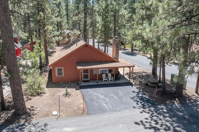 chalet / cabin featuring aphalt driveway and a chimney