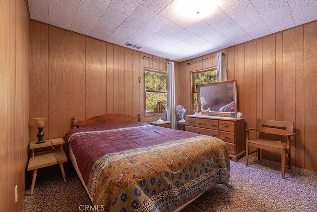 carpeted bedroom featuring visible vents and wood walls