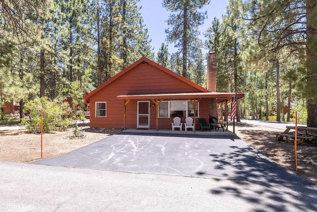 chalet / cabin featuring a porch and a chimney