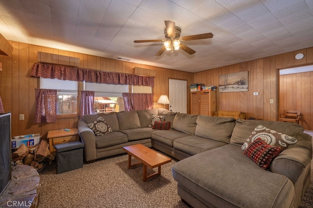 carpeted living room with ceiling fan and wooden walls