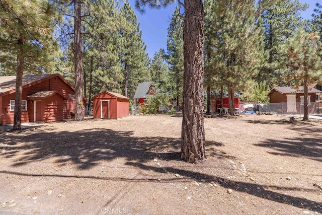 view of yard with an outbuilding, fence, and a storage shed