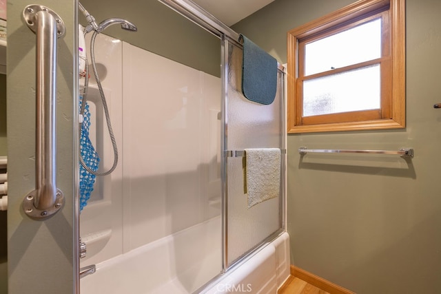 bathroom with combined bath / shower with glass door and wood-type flooring