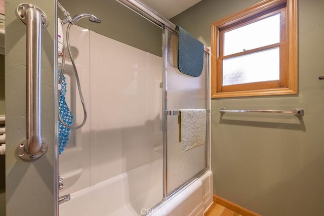 full bath with bath / shower combo with glass door and baseboards