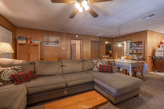 living room featuring wood walls, carpet floors, and ceiling fan