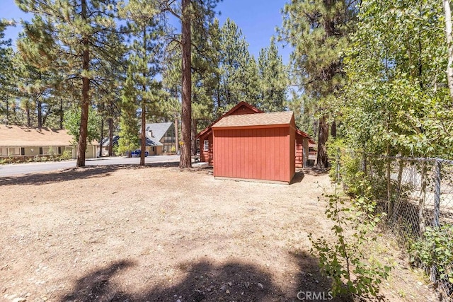 view of yard featuring an outbuilding, a storage shed, and fence