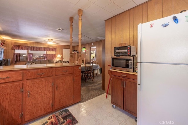 kitchen with ceiling fan, wooden walls, white refrigerator, and light tile patterned floors