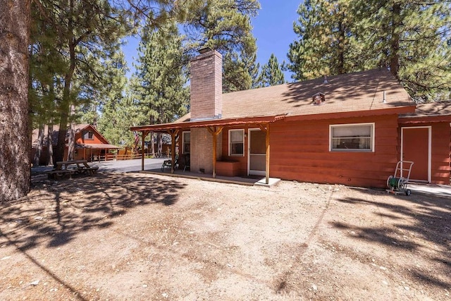 rear view of property featuring a patio area and a chimney