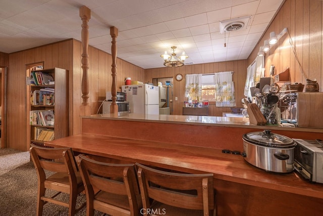 kitchen featuring kitchen peninsula, wooden walls, carpet floors, and white refrigerator