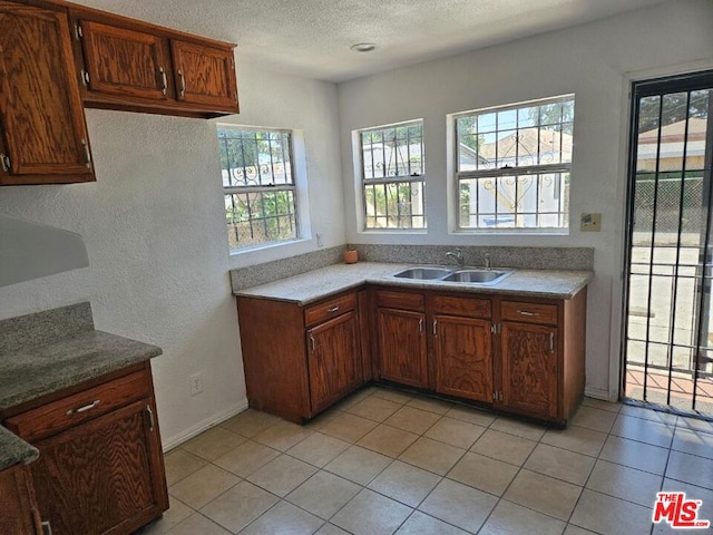 kitchen with light tile patterned floors, sink, a textured ceiling, and plenty of natural light