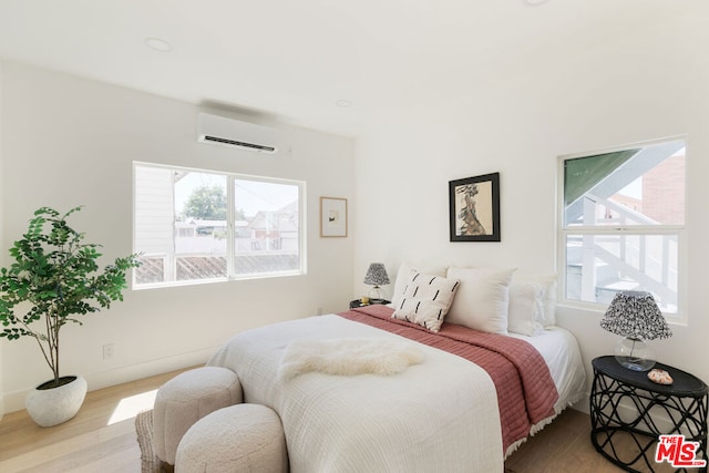 bedroom with hardwood / wood-style floors and a wall mounted AC